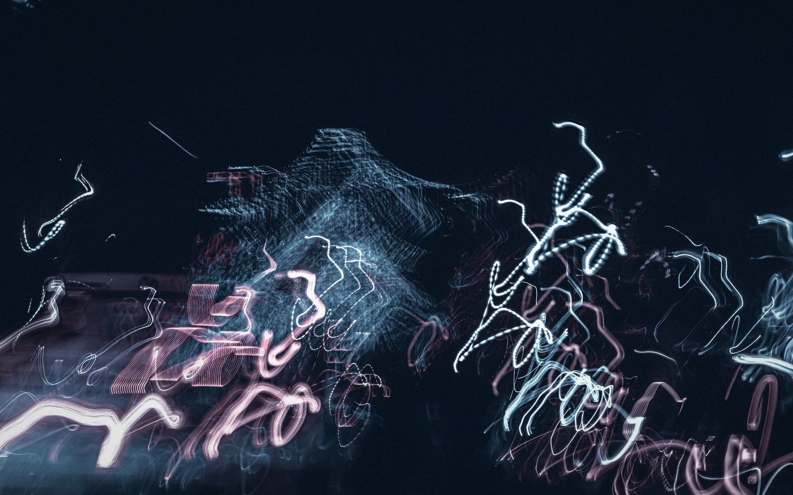 Squiggly white and pink light trails swirl against a dark night cityscape