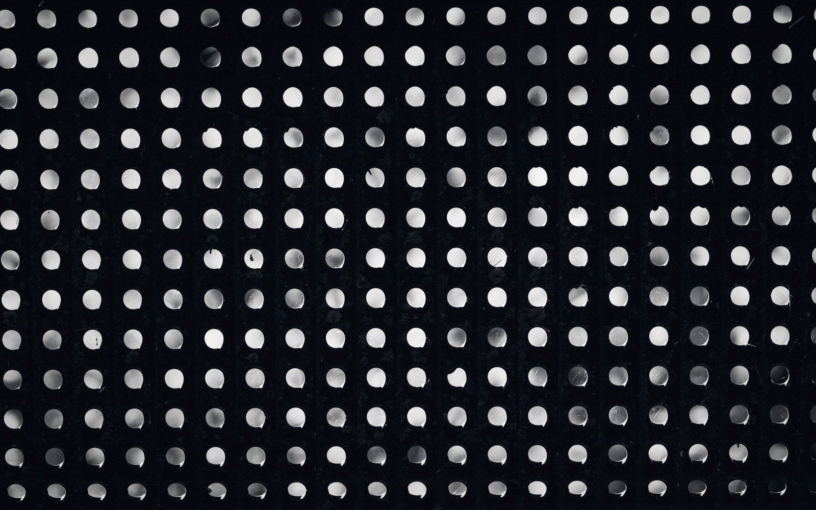 Rows of evenly spaced white dots forming a grid pattern on a black surface