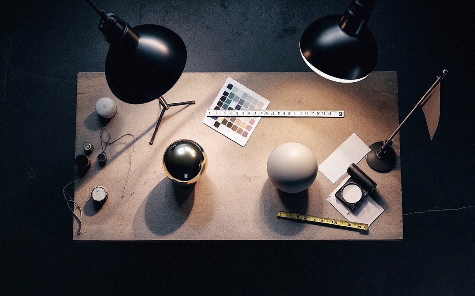 Overhead view of a chrome sphere and a matte grey sphere on a lit studio desk with lamps and a color chart